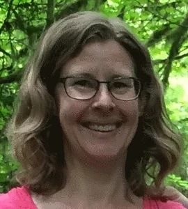 Molly Rhoten, Owner of The Trip Clip® - head shot, wearing glasses, green leaves in the background