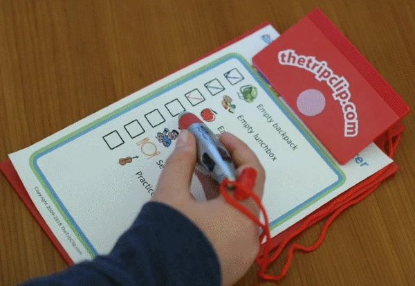 Red, kid-sized clipboard holding picture checklist, kid hand holding attached 4-click pen